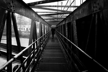 Lone Figure on Metal Bridge - Black and White Perspective