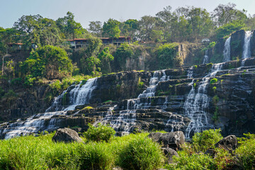 Tiered waterfall tumbling over basalt cliffs beneath a forested ridge, Pongour Waterfall, Vietnam