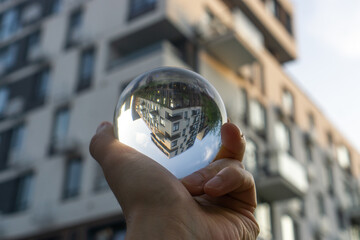 hand holding a glass ball with apartment complex on the background