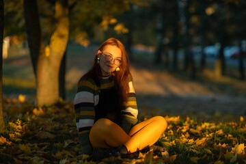 Portrait of a young beautiful red-haired girl in an autumn city park.