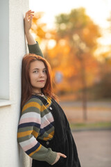Portrait of a young beautiful red-haired girl in an autumn city park.