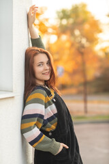 Portrait of a young beautiful red-haired girl in an autumn city park.