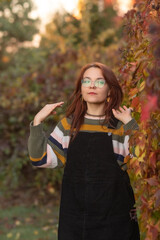 Portrait of a young beautiful red-haired girl in an autumn city park.
