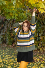 Portrait of a young beautiful red-haired girl in an autumn city park.