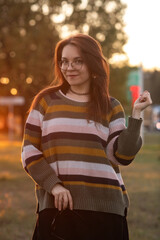 Portrait of a young beautiful red-haired girl in an autumn city park.