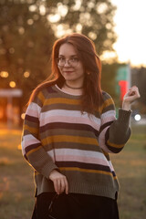 Portrait of a young beautiful red-haired girl in an autumn city park.