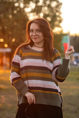 Portrait of a young beautiful red-haired girl in an autumn city park.