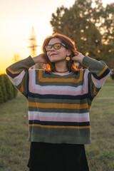 Portrait of a young beautiful red-haired girl in an autumn city park.