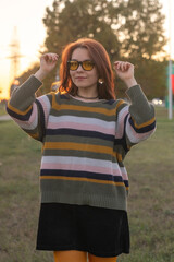 Portrait of a young beautiful red-haired girl in an autumn city park.
