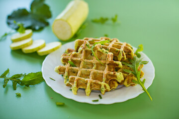 Vegetable zucchini waffles with greens on a green background