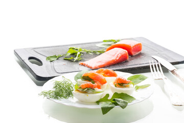 Egg halves with red salmon and herbs on a white background