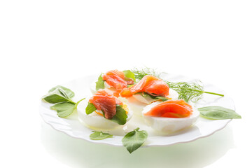 Cold festive appetizer of eggs with fish slices on a white background