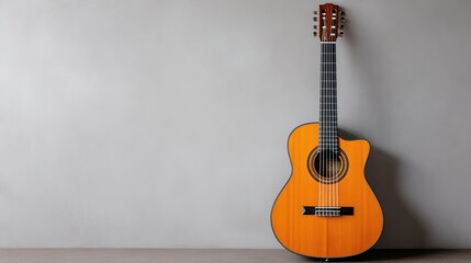Fototapeta premium An acoustic guitar rests against a smooth gray wall, showcasing its rich wood finish and intricate details. The scene highlights the elegance of musical craftsmanship