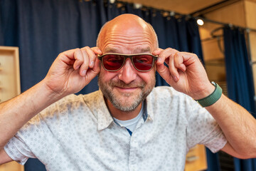 Happy man with bald head and sun glasses at shop 