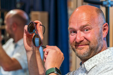 Happy man with bald head and sun glasses at shop 