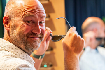 Happy man with bald head and sun glasses at shop 