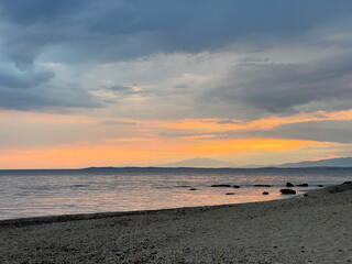 Sunset over the sea with waves hitting the shore 