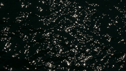 Water surface high contrast top view. Sun glare on water black and white edit. Background abstracted wallpaper texture