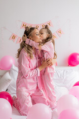 little girl celebrates her birthday morning in pink pajamas with her mom