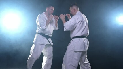 Martial arts masters on dark background. Strong man fighters in white kimono for karate martial arts fighting training in black gym. Karate fighters training punches kicks practicing fight sparring - Powered by Adobe