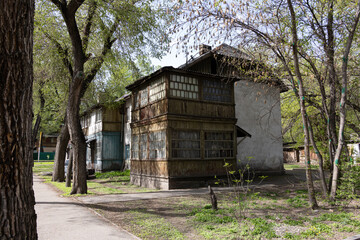 Old wooden residential building with enclosed balconies and glass windows surrounded by spring trees
