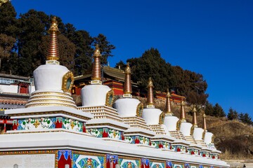 Colorful Tibetan stupas at Taktsang Lhamo Monastery in Langmusi, Amdo region, showcasing traditional Buddhist architecture and intricate cultural details.