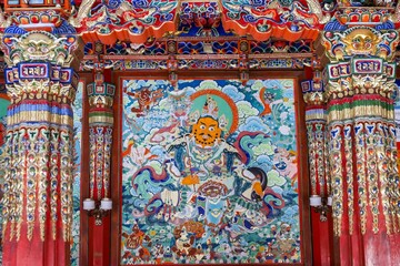 Colorful Tibetan Buddhist mural depicting a fierce deity at Taktsang Lhamo Monastery in Langmusi, Amdo region, showcasing intricate traditional temple artwork and vibrant religious symbolism