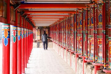 A pilgrim walks beside the longest Tibetan prayer wheels at Labrang Monastery during the Butter Lamp Festival in Amdo, a historic region of Greater Tibet.