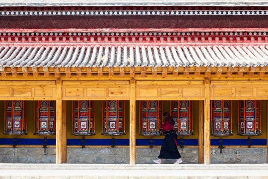 An female pilgrim pushing the longest Tibetan prayer wheels in the world at Labrang Monastery, one of the largest monastery in Amdo region (now Gansu) during Butter Lamp Festival. 