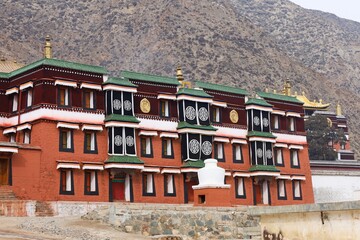 Traditional Tibetan architecture of Labrang Monastery, a major Gelug school monastery and cultural landmark in Amdo region (Gansu), showcasing vibrant red walls and intricate window designs.