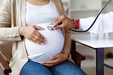 Male Doctor With Stethoscope Examining Belly Of Pregnant Female Patient, Obstetrician Listening Baby's Heartbeat While Making Check Up To Pregnant Woman In Maternity Clinic, Closeup