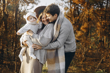 Happy family hugging with little baby son in autumn field in soft evening light. Parenthood. Mother...