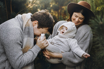 Happy family hugging with cute baby son in autumn woods in soft evening light. Parenthood. Mother...