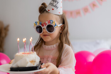 little girl blows out the birthday cake at home