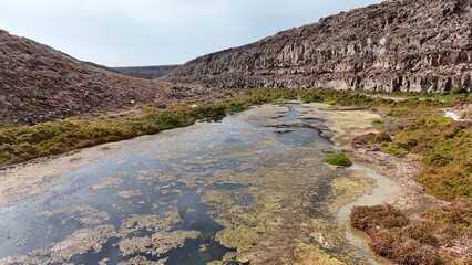 volcanic arid landscapes with trils, cliffs, and scattedred vegetation.