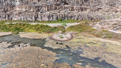 volcanic arid landscapes with trils, cliffs, and scattedred vegetation.