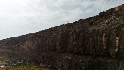 volcanic arid landscapes with trils, cliffs, and scattedred vegetation.