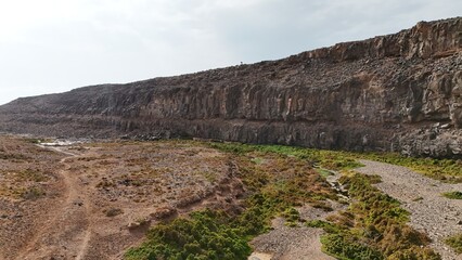 volcanic arid landscapes with trils, cliffs, and scattedred vegetation.