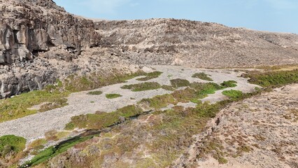 volcanic arid landscapes with trils, cliffs, and scattedred vegetation.