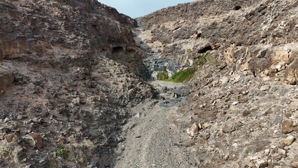 volcanic arid landscapes with trils, cliffs, and scattedred vegetation.