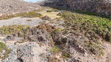 volcanic arid landscapes with trils, cliffs, and scattedred vegetation.