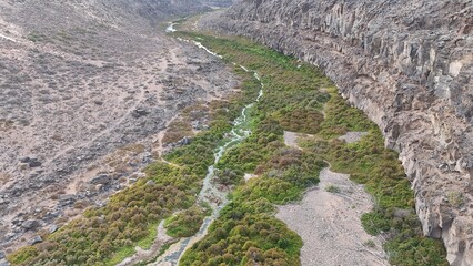 volcanic arid landscapes with trils, cliffs, and scattedred vegetation.