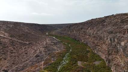 volcanic arid landscapes with trils, cliffs, and scattedred vegetation.