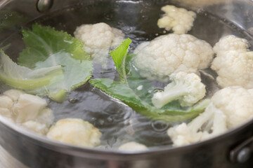 Fresh cauliflower is boiled in a saucepan with water. The vegetable is divided into florets and...