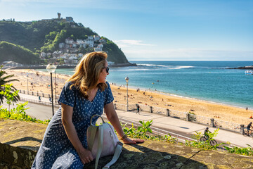 Fototapeta premium Woman in dress enjoying a sunny day on the beach in Ondarreta, San Sebastian, Basque Country.