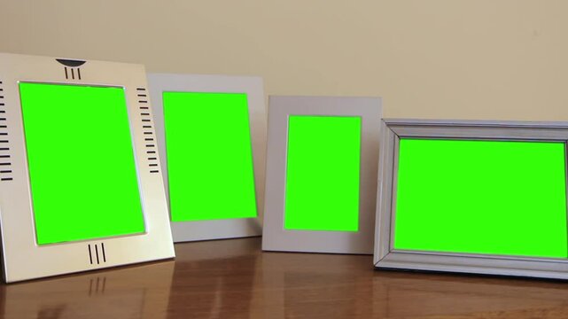 Four White Picture Frames With Green Screen on Shelf in Living Room - Close Up