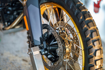 Fototapeta premium Detailed close-up of a motorcycle wheel showing brake system and tire tread patterns in a workshop setting