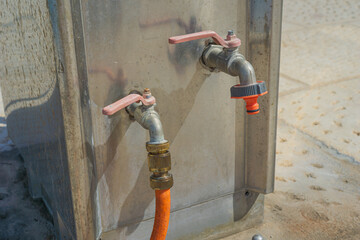 Two metal water taps with hose connections on a marina dock, used for supplying fresh water to...