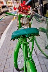 Close-up bright-green vintage road bicycle repurposed as street decor outside a cafe, adorned with flowers, showcasing creative urban design and charm in a lively outdoor setting
