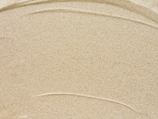 Beach sand background with natural wave pattern. Summer background of beach sand with small stones along the edges. Tourism, vacation and holidays concept. Top view.